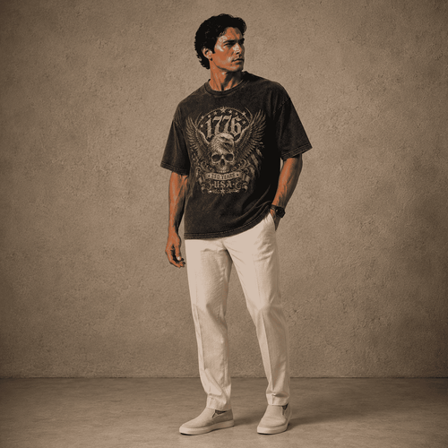 Man wearing a USA 250th Anniversary Shirt graphic t-shirt and light pants against a textured wall.