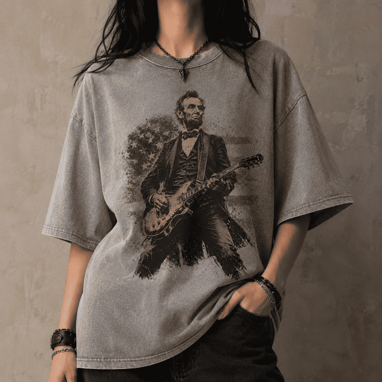 Person wearing a gray t-shirt with a graphic of Abraham Lincoln playing a guitar against a textured wall.