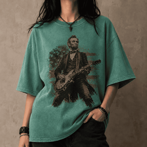 Person wearing a teal t-shirt with a graphic of Abraham Lincoln playing a guitar against a plain background