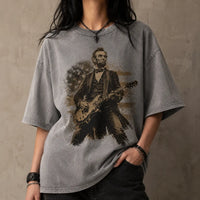 Person wearing a gray t-shirt with a graphic of Abraham Lincoln playing a guitar against a textured wall.