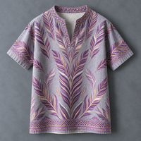 A short-sleeve linen tunic shirt in light gray with a purple, pink, and beige feather pattern and geometric border details, displayed flat against a dark gray background.