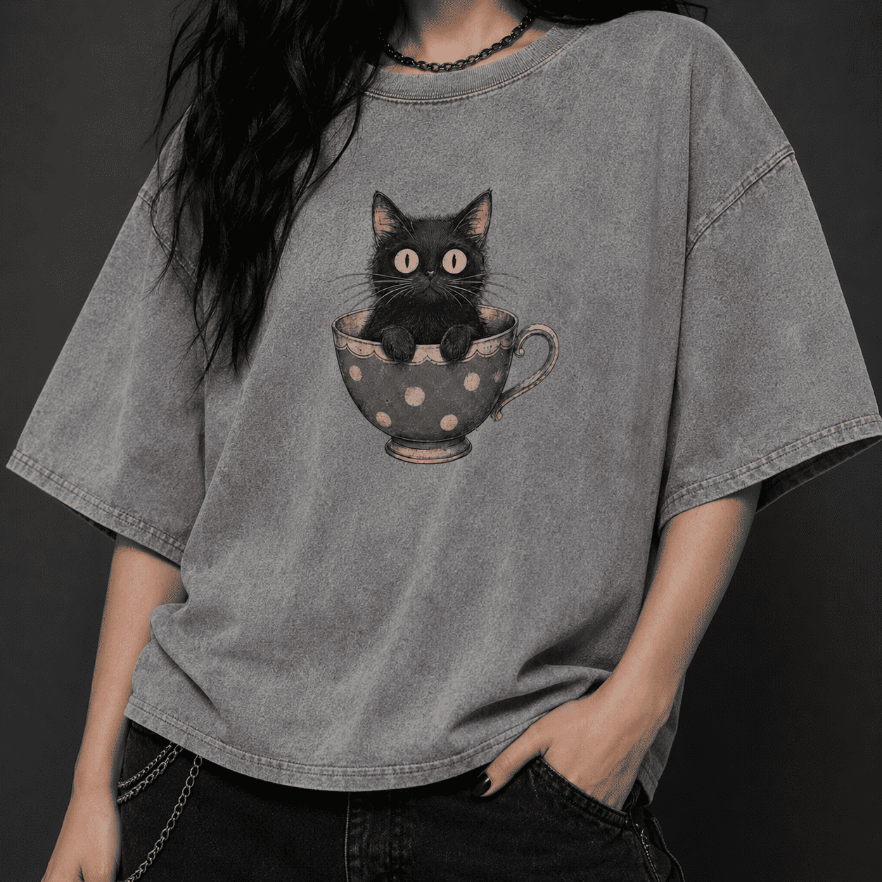 Person wearing a gray t-shirt with a black cat in a teacup design.