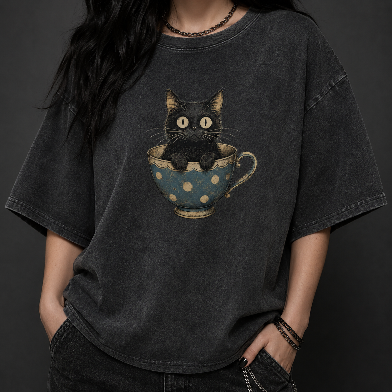 Person wearing a black t-shirt with a graphic of a cat in a teacup on a dark background