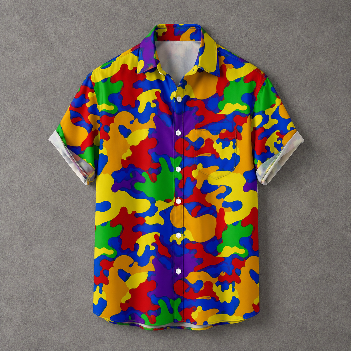 A short-sleeve button-up camp shirt with a vibrant, multicolor abstract camouflage pattern in yellow, blue, red, green, and purple, laid flat on a textured gray background.