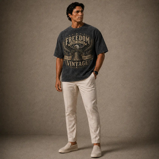 Man wearing a graphic t-shirt and light pants against a plain background