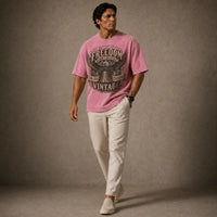 Man wearing a pink t-shirt with text and graphics, standing against a plain background