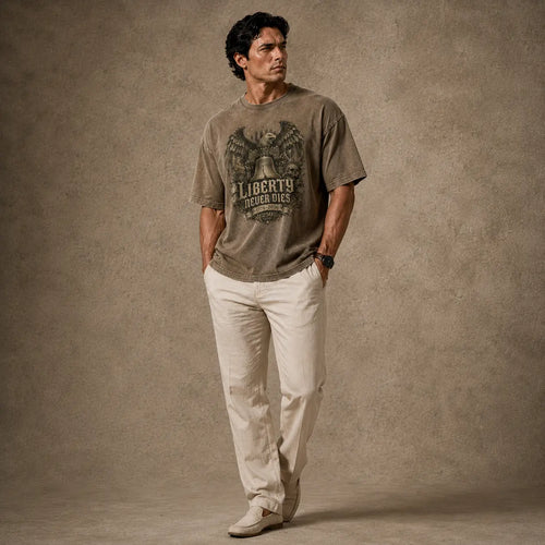 Man wearing a graphic t-shirt and light-colored pants against a textured brown background