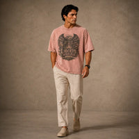 Man wearing a pink t-shirt with a graphic design and text, standing against a plain background