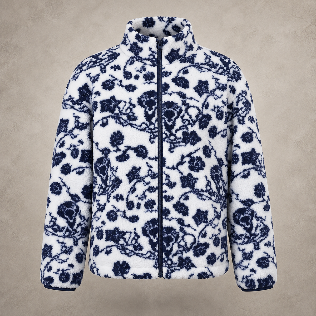 A white fleece jacket with a navy blue floral and branch pattern, featuring a full front zipper and stand-up collar, shown against a textured beige background.