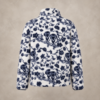 A white fleece jacket with a navy blue floral toile pattern, shown from the back against a textured beige background.