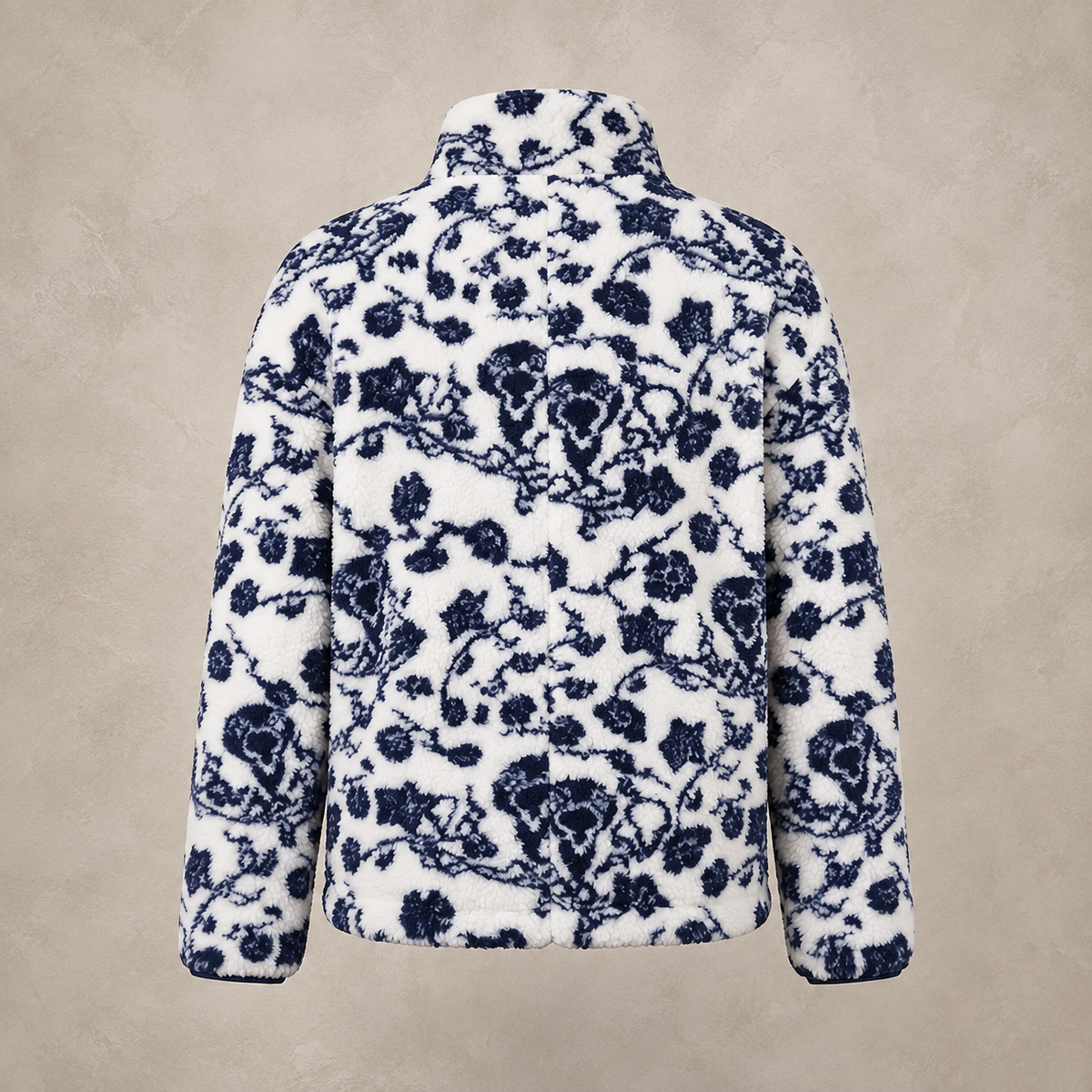 A white fleece jacket with a navy blue floral toile pattern, shown from the back against a textured beige background.