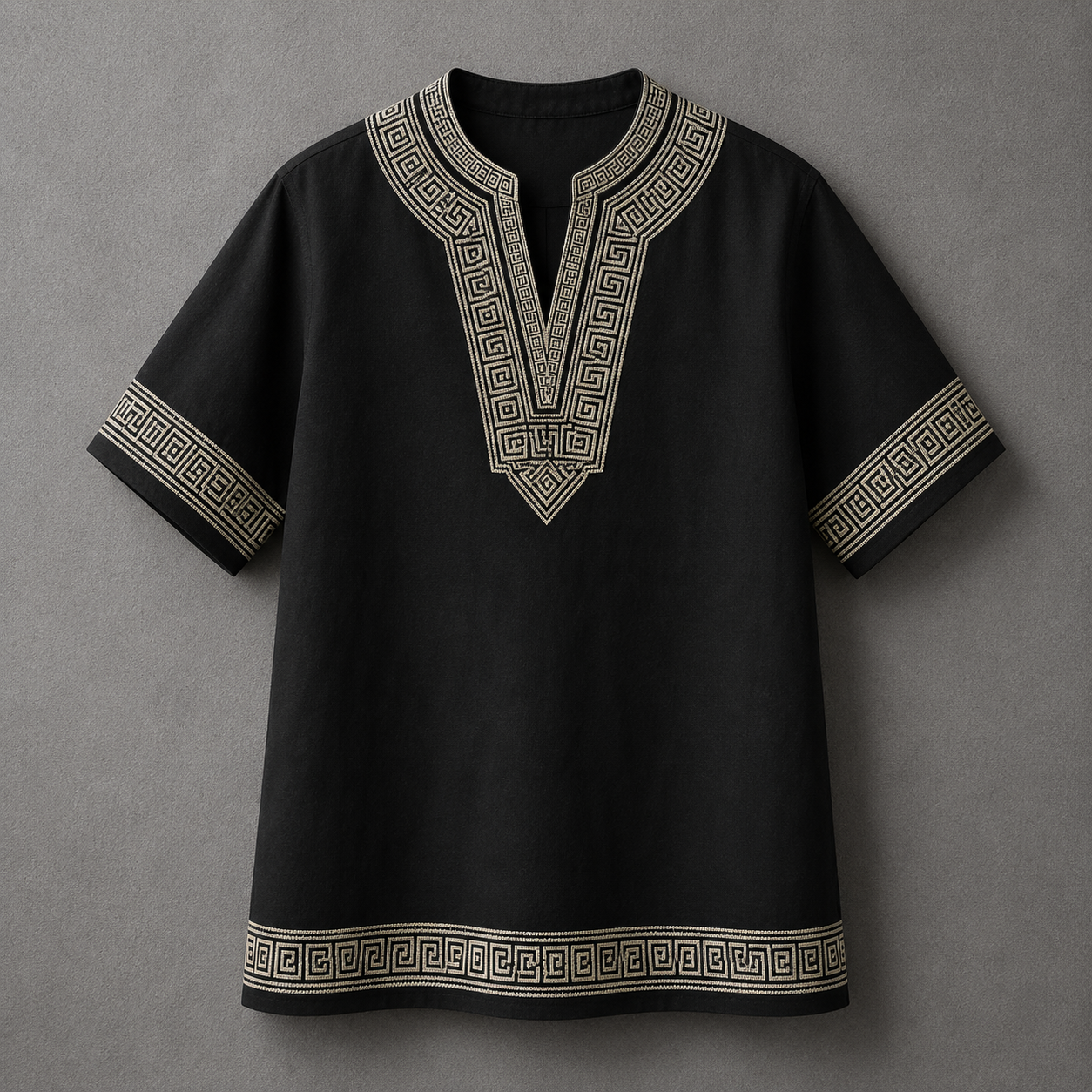 A black short-sleeve tunic top with beige Greek key pattern embroidery on the V-neck, sleeve cuffs, and hem, displayed against a neutral gray background.