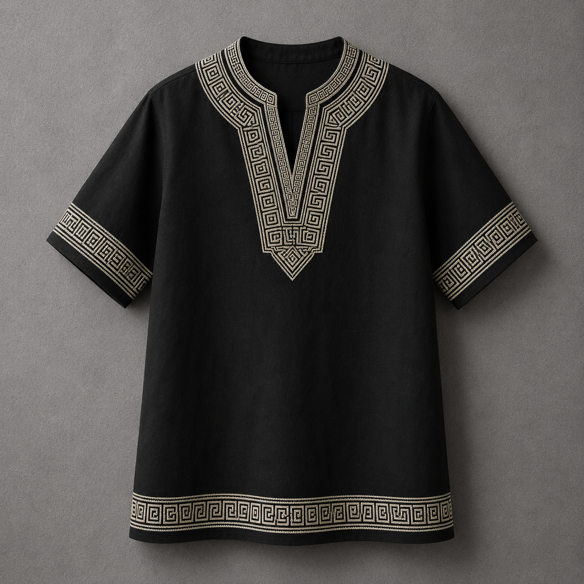 A black short-sleeve tunic top with beige Greek key pattern embroidery on the V-neck, sleeve cuffs, and hem, displayed against a neutral gray background.