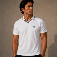 Man wearing a white polo shirt with a logo on a beige background