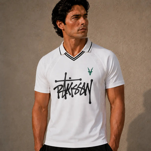 Man wearing a white polo shirt with black text and green logo against a beige background