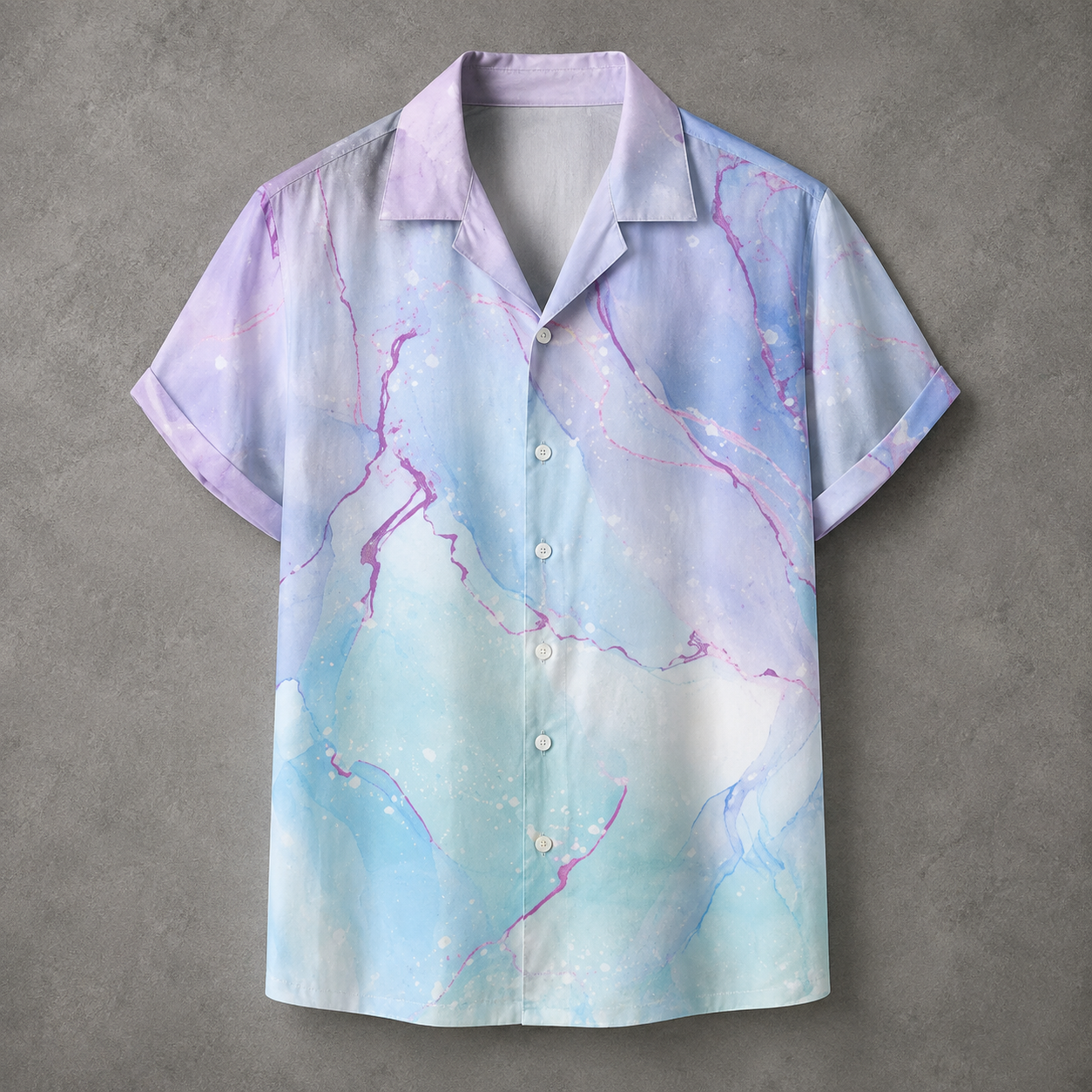 A short-sleeve button-up camp shirt with a pastel purple and light blue watercolor marble print, laid flat on a textured gray background.