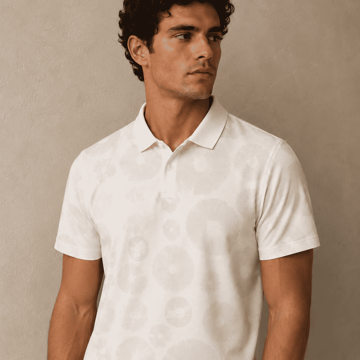 Man wearing a white polo shirt against a beige background