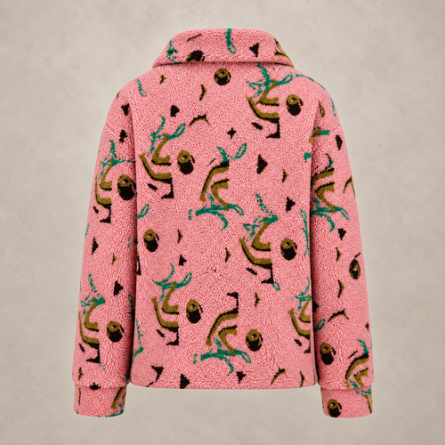A pink sherpa fleece jacket with an all-over whimsical print of dancing figures, acorns, and small black shapes, shown against a neutral textured beige background.
