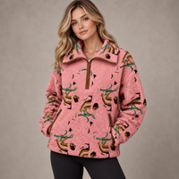 A woman wearing a pink sherpa fleece quarter-zip pullover with a brown collar, zipper, and pocket trim, decorated with a green and brown abstract pattern, set against a neutral gray studio background.
