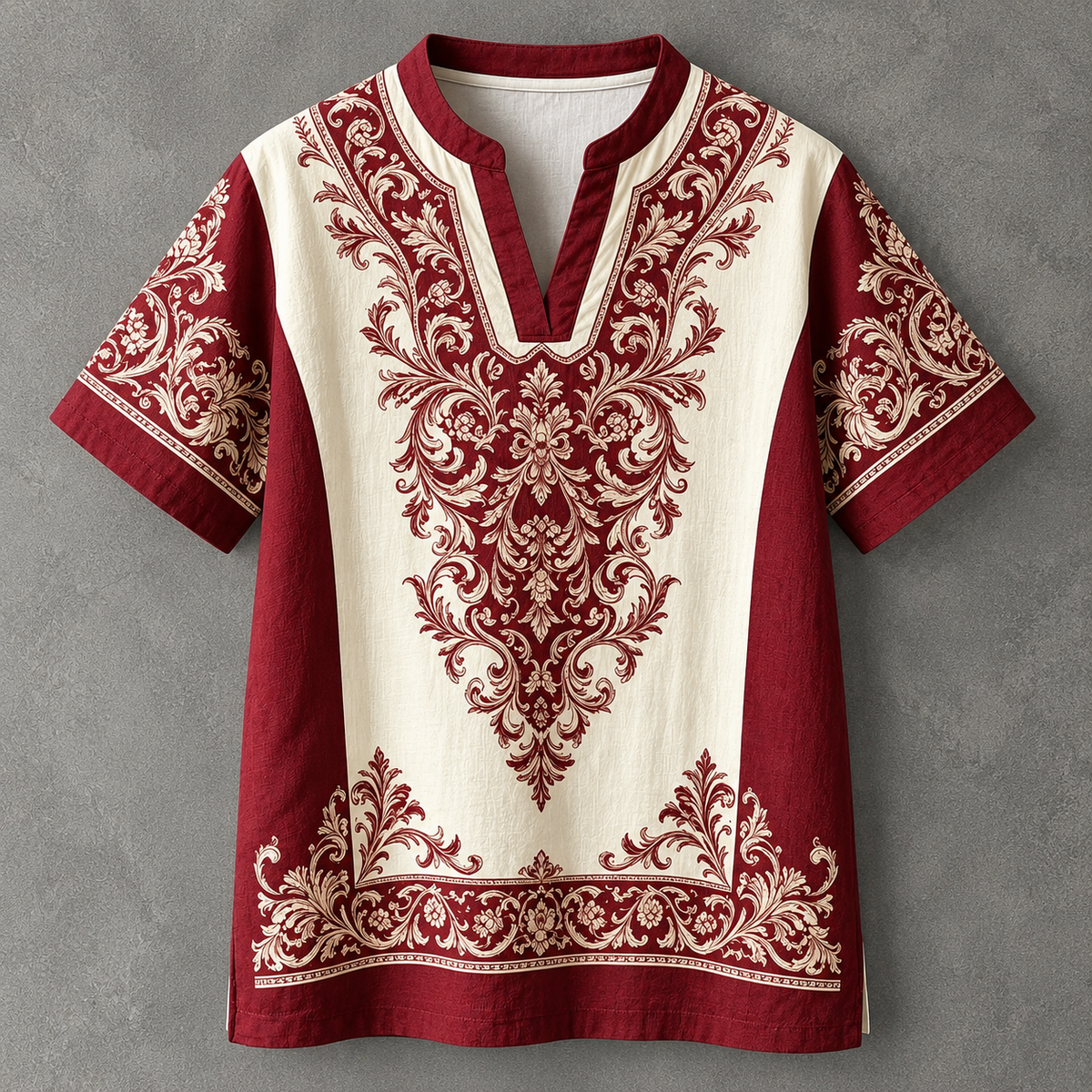 A short-sleeve tunic top with a deep V-neck, featuring a cream-colored center panel and sleeves with deep red damask-style embroidery, set against a textured gray background.