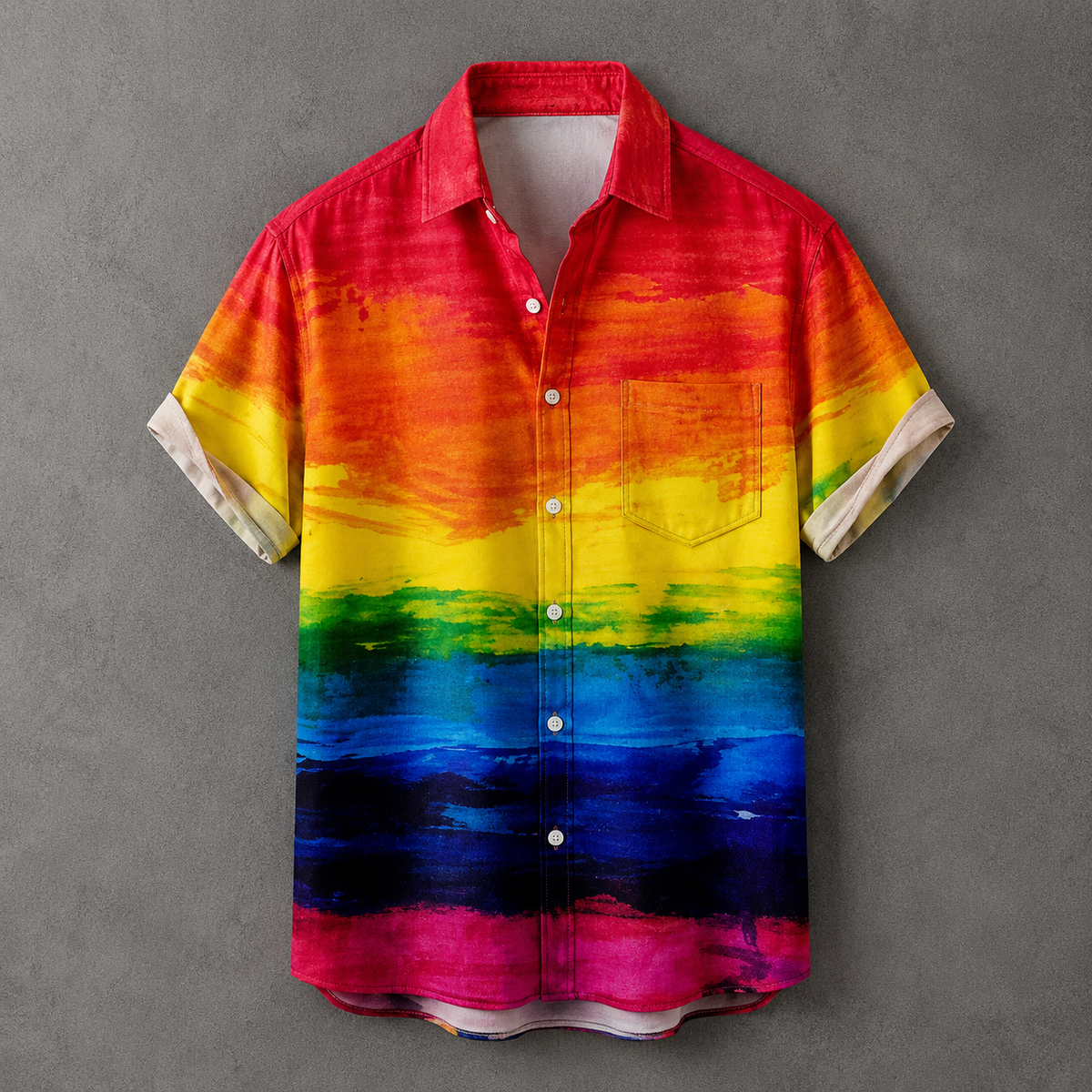 A short-sleeve button-up shirt with a vibrant rainbow watercolor print, featuring a red, orange, yellow, green, blue, and pink gradient design, displayed against a textured gray background.