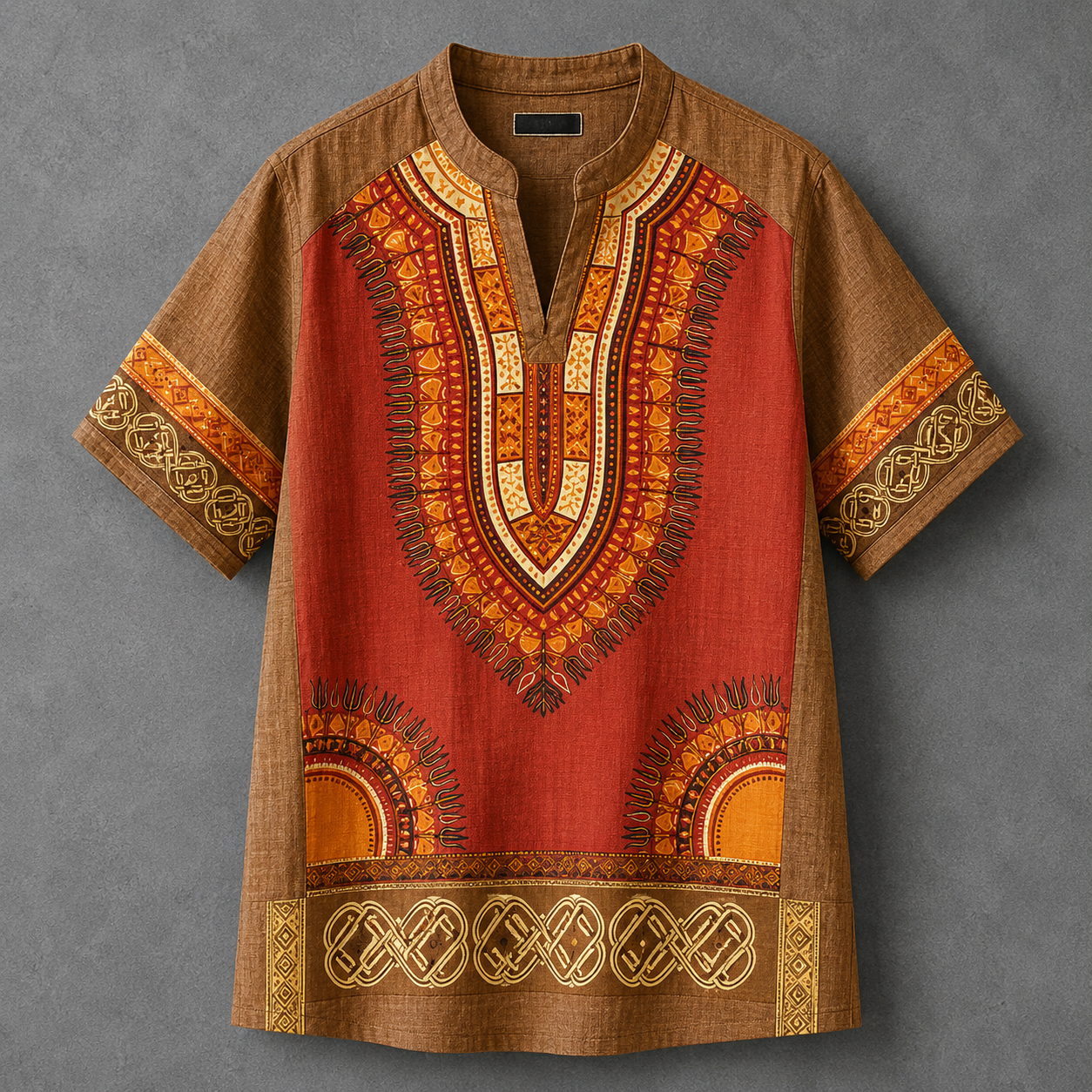 A short-sleeve dashiki tunic shirt with a brown base and a vibrant red-orange central panel decorated with intricate yellow, orange, and gold geometric patterns, laid flat on a textured gray background.