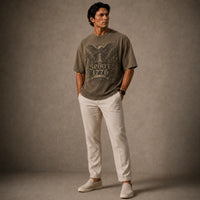 Man wearing a graphic t-shirt and white pants against a gray background