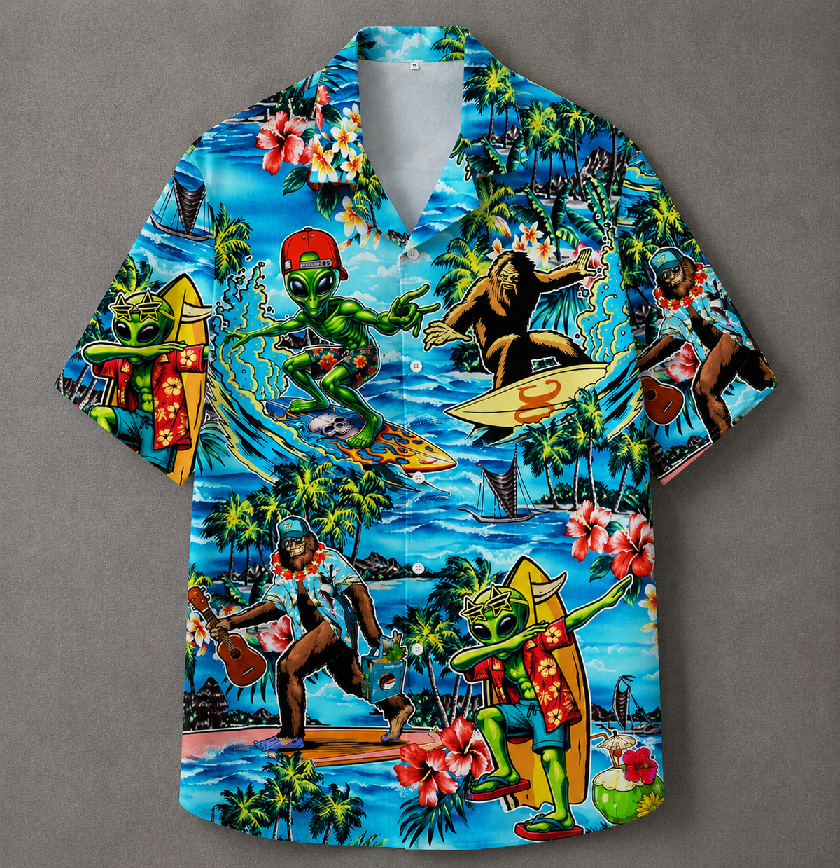 A short-sleeve button-up Hawaiian shirt with a vibrant, detailed graphic print featuring green aliens, surfers, palm trees, and beach scenes on a blue ocean background, displayed flat against a neutral gray backdrop.