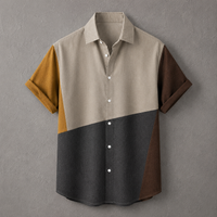 A men's short-sleeve button-up shirt with a color-blocked design, featuring a light beige upper body, a dark charcoal lower body, and mustard yellow and dark brown sleeve panels, shown against a textured gray background.