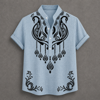 A light blue short-sleeve button-up shirt with black ornate paisley and floral embroidery on the front, displayed flat against a textured gray background.