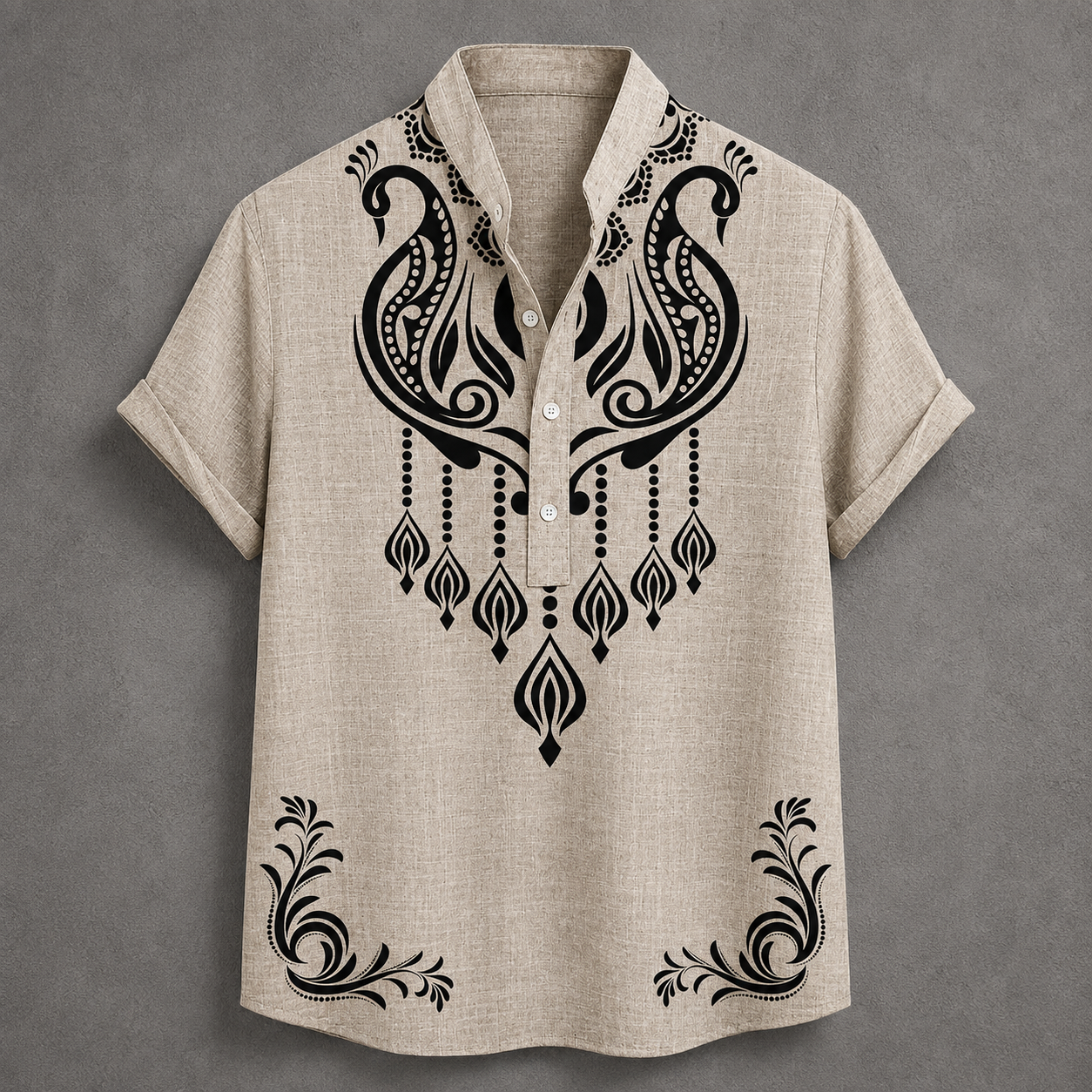 A beige short-sleeve button-up shirt with black ornate tribal-style embroidery on the chest and lower hem, displayed flat against a textured gray background.
