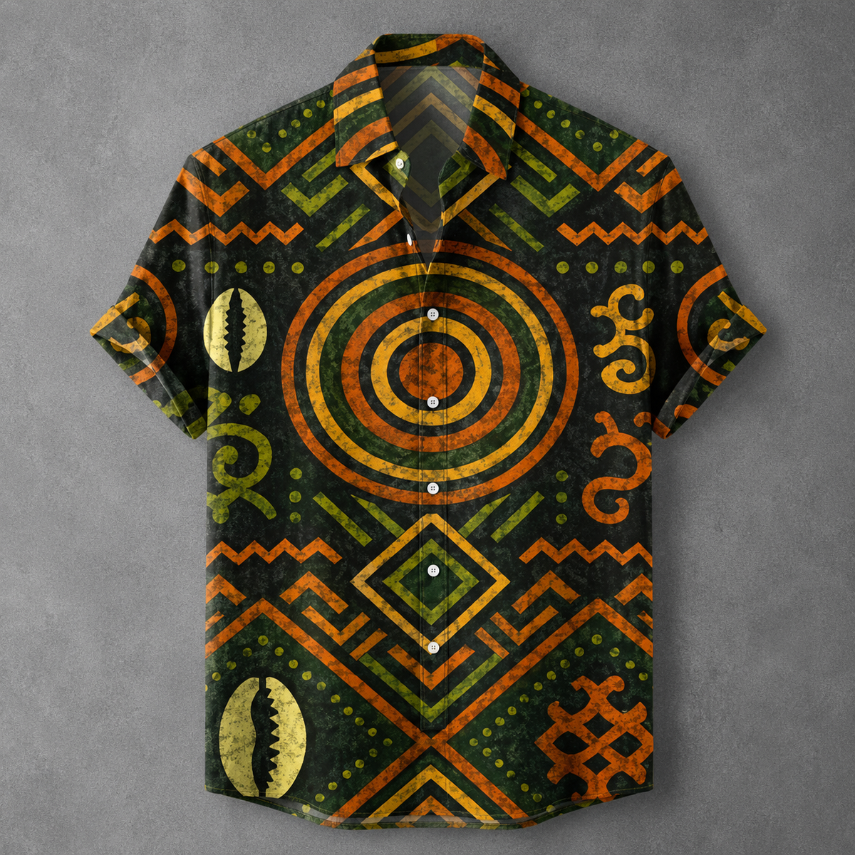 A short-sleeve button-up shirt with an all-over African tribal-inspired pattern in orange, olive green, and black, featuring geometric designs, spirals, and shell motifs, displayed on a textured gray background.