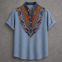 A light blue short-sleeve button-up shirt with a dark blue collar and a vibrant, multicolored African dashiki-style embroidered yoke on the chest, displayed flat against a textured gray background.