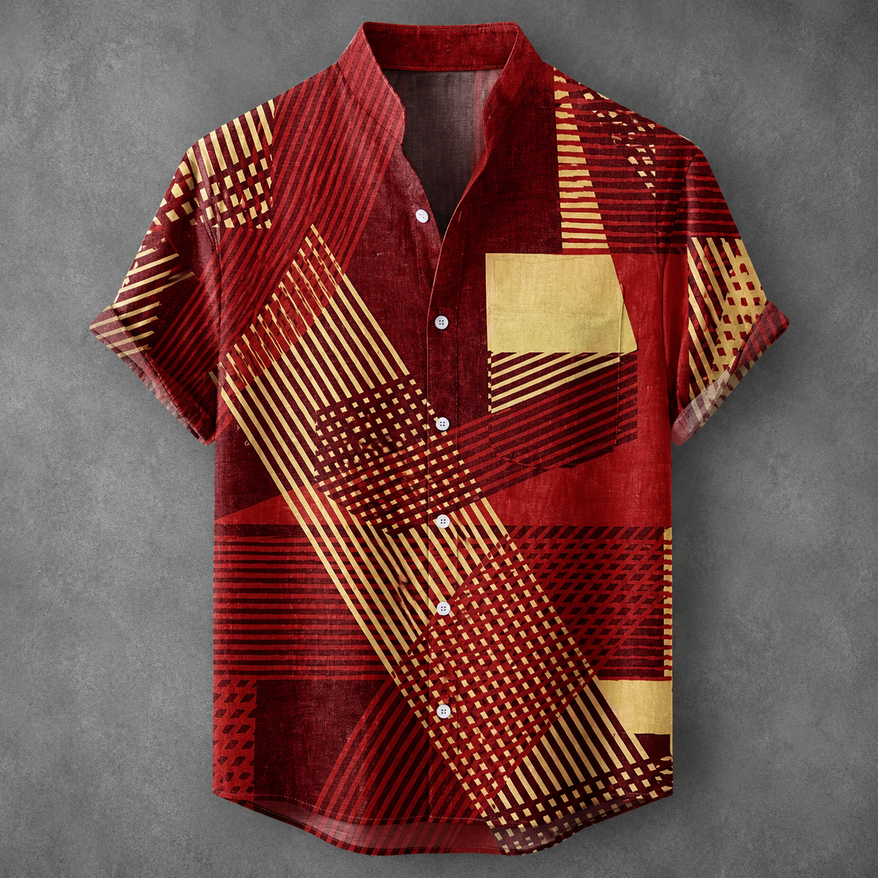 A short-sleeve button-up shirt with a bold geometric pattern in red and gold, laid flat against a textured gray background.