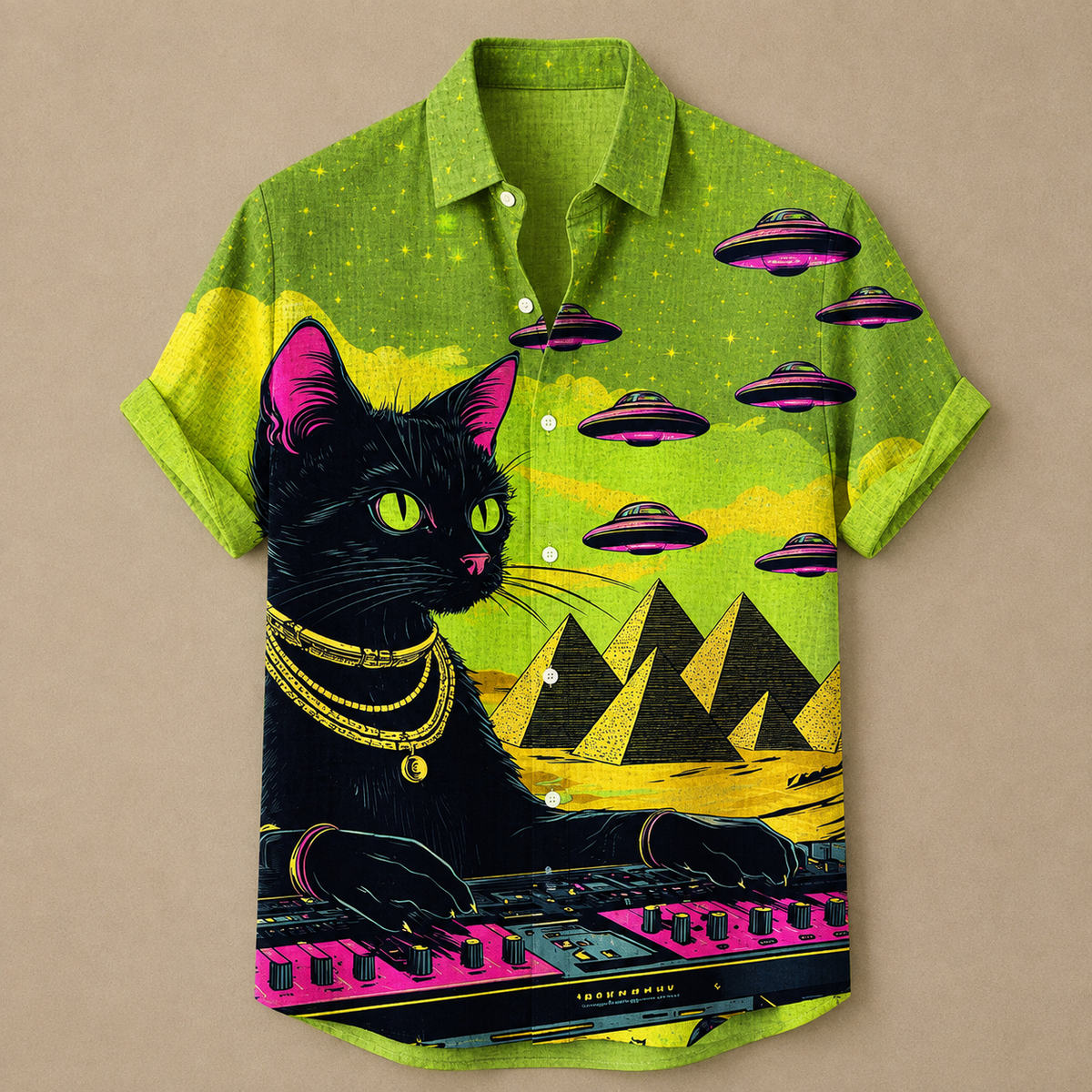 A short-sleeve button-up shirt with a vibrant graphic print featuring a black cat playing a pink keyboard, with pink and black flying saucers, yellow pyramids, and a lime green starry sky on a beige background.