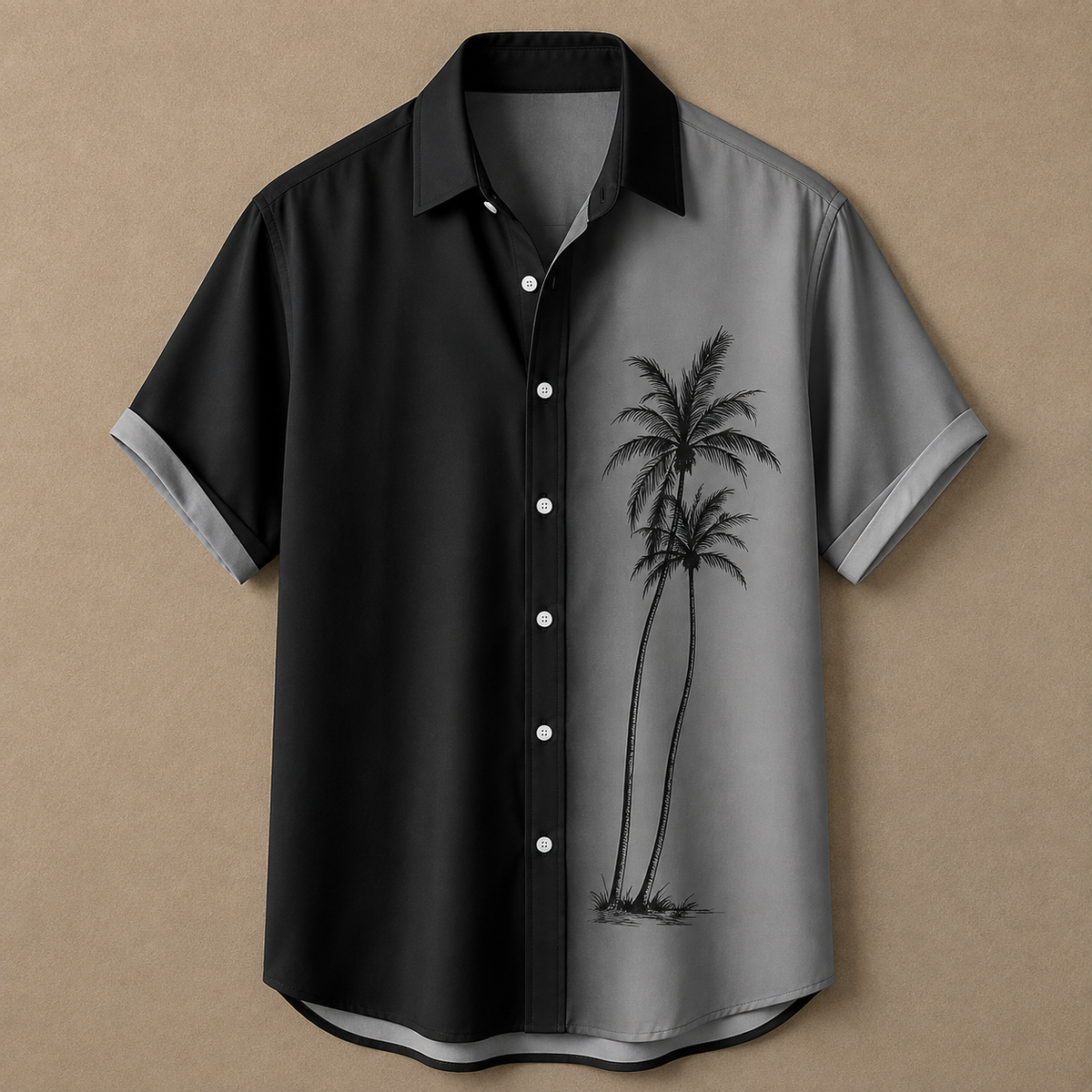 A short-sleeve button-up shirt with a split black and gray design, featuring a black palm tree graphic on the gray side and white buttons, displayed against a textured tan background.