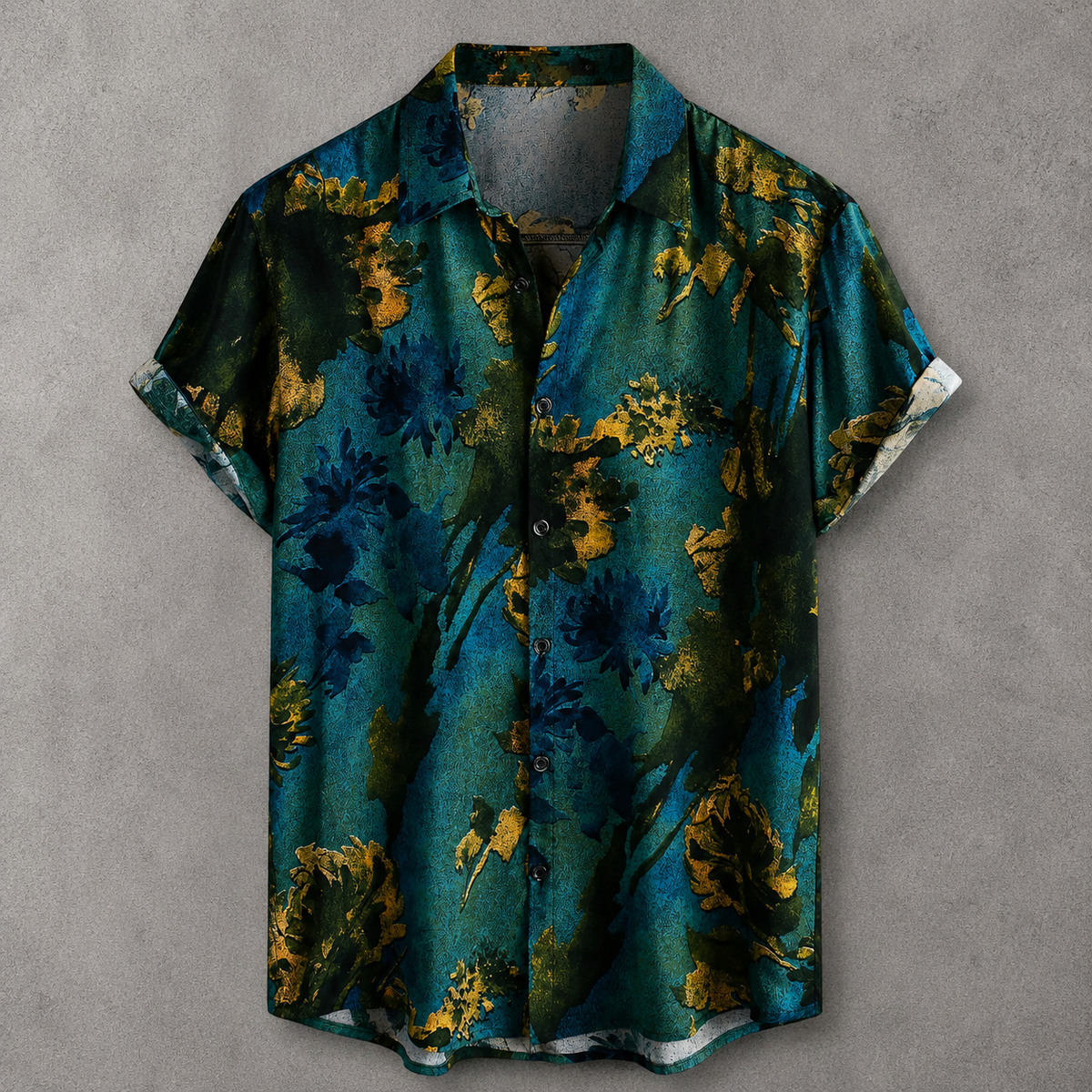 A short-sleeve button-up shirt with a dark teal and black abstract floral pattern accented by gold, laid flat on a textured gray background.