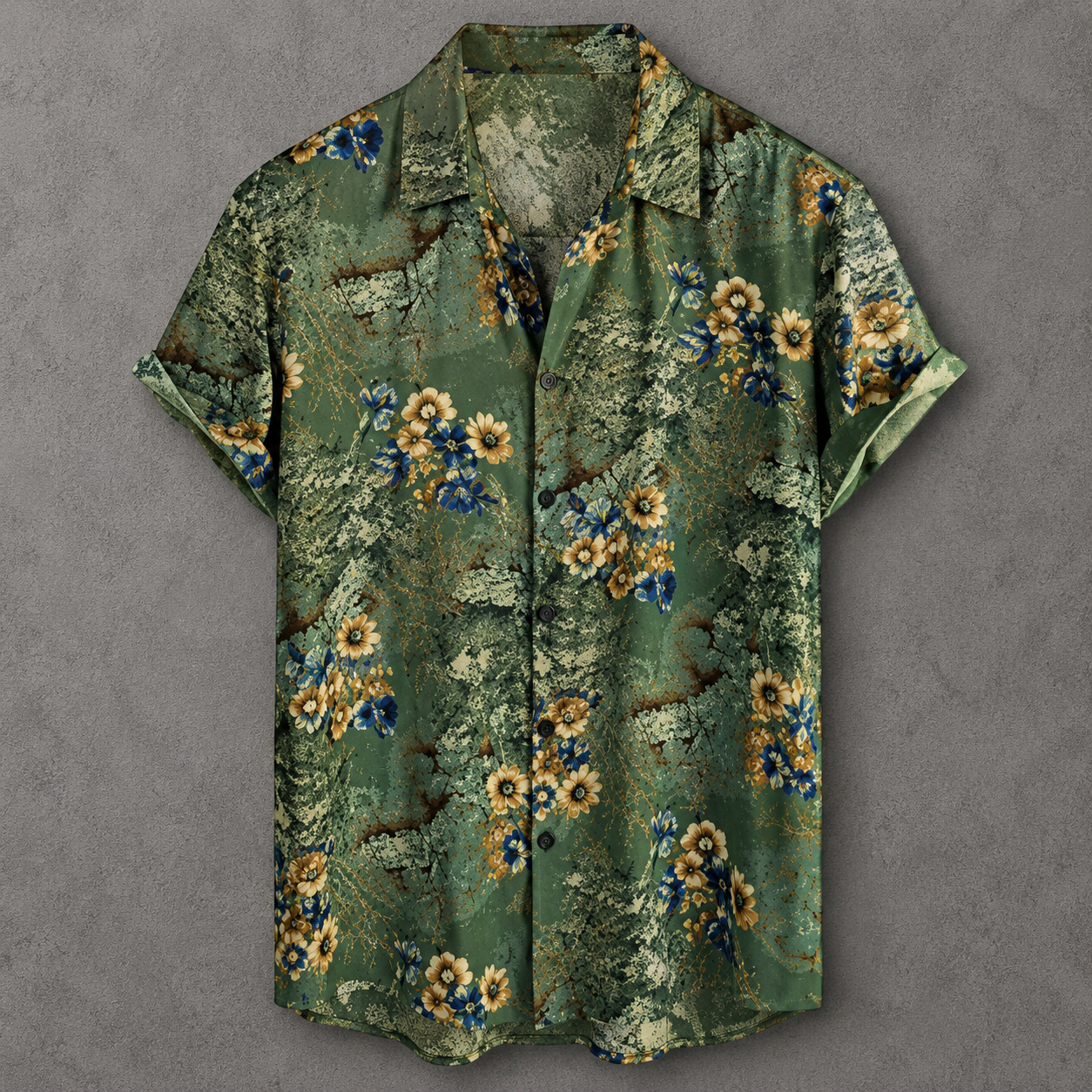 A short-sleeve button-up camp shirt with a green tropical floral and foliage print, featuring yellow and blue flowers, laid flat on a textured gray background.