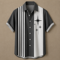 A short-sleeve button-up shirt with a dark gray and white vertical split design, featuring black stripes on the left side and black starburst graphics on the right side, displayed against a solid tan background.