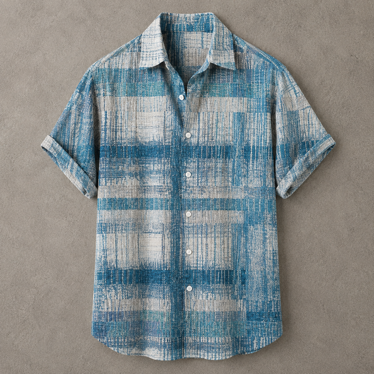 A short-sleeve button-up shirt with a blue and off-white textured plaid pattern, laid flat on a textured gray background.