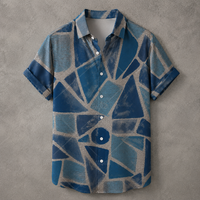 A short-sleeve button-up shirt with a blue and gray geometric mosaic pattern, laid flat on a textured gray background.