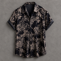 A short-sleeve button-up shirt with a dark navy and beige botanical leaf pattern, laid flat against a textured gray background.