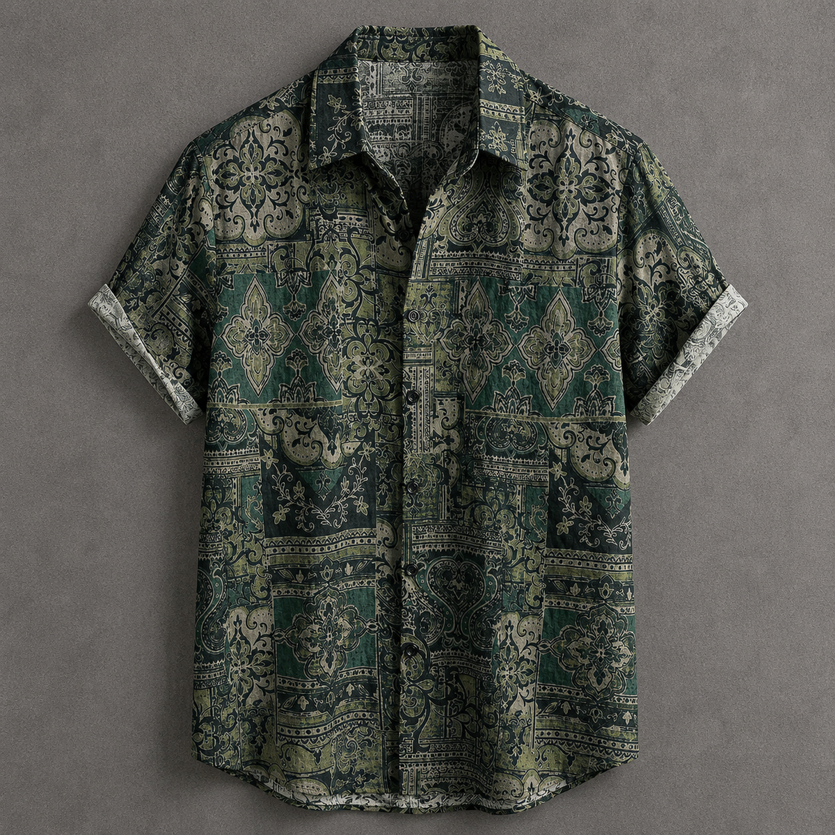 A short-sleeve button-up shirt with a dark green and beige bohemian-style geometric pattern, laid flat on a textured gray background.