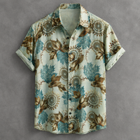 A short-sleeve button-up shirt with a light beige background and an all-over botanical pattern featuring blue-green leaves and brown floral motifs, laid flat against a textured gray background.