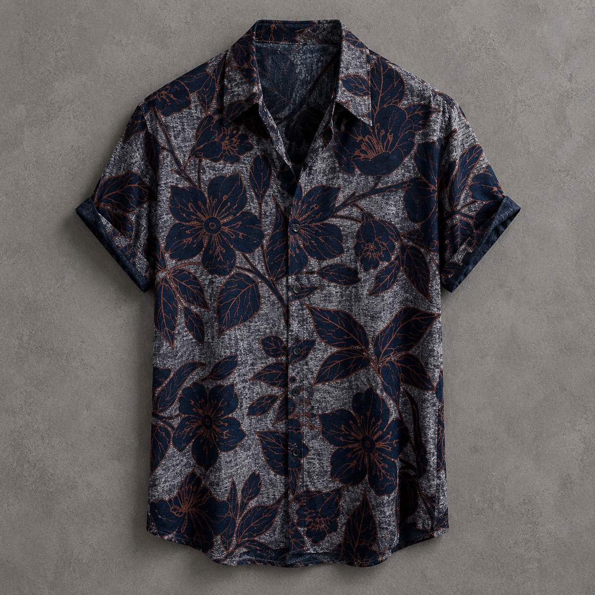 A short-sleeve button-up shirt with a dark navy blue floral pattern over a textured gray background, laid flat on a gray textured surface.