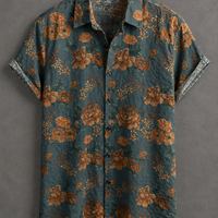 A short-sleeve button-up shirt with an all-over floral print in rust orange and green on a dark teal-blue background, displayed flat against a textured gray backdrop.