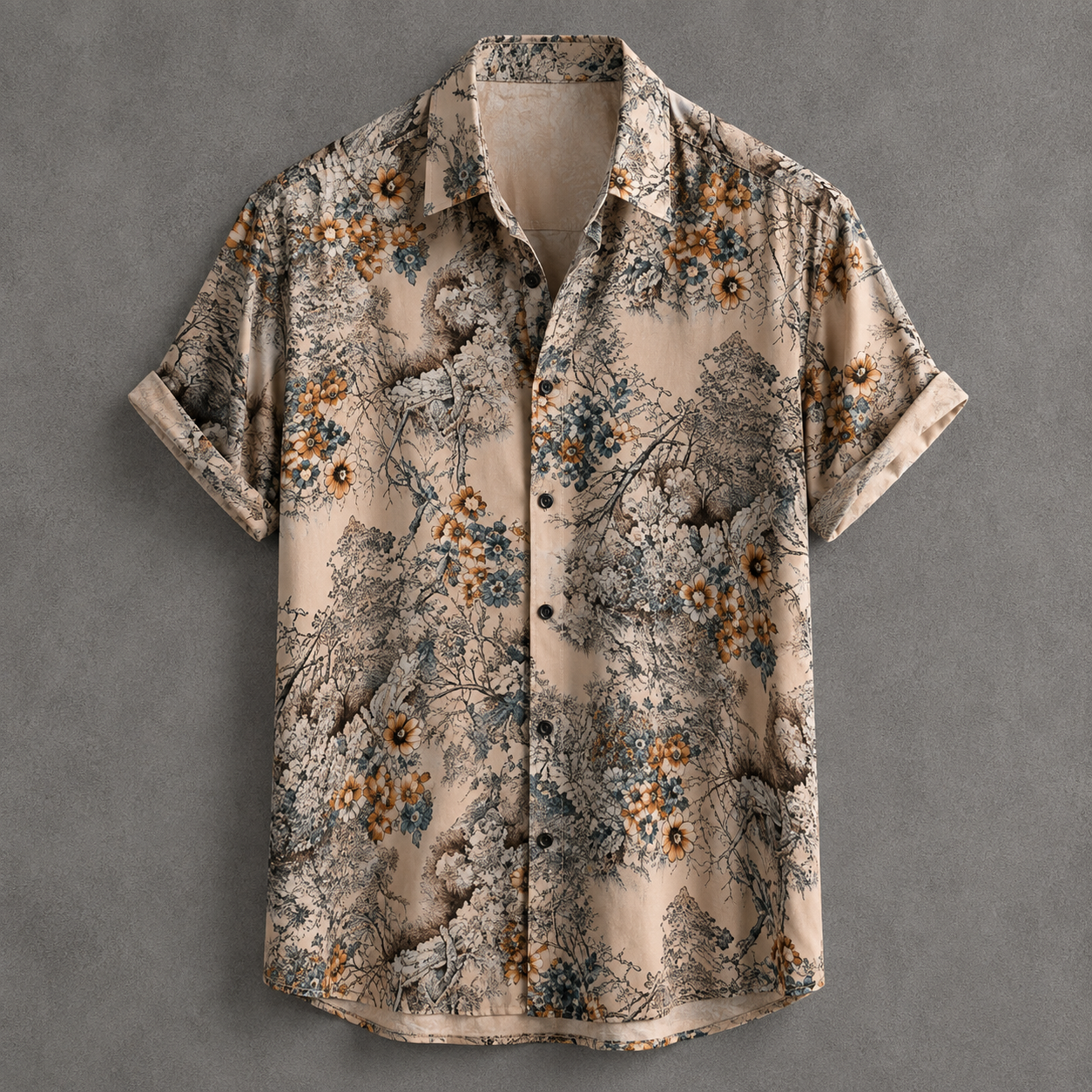 A short-sleeve button-up shirt with a detailed scenic print of mountains, forests, and wildflowers in earthy tones of beige, brown, blue, and orange, laid flat against a textured gray background.