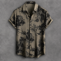 A short-sleeve button-up shirt with a black tropical floral and bamboo print on a muted olive-beige background, displayed flat against a textured gray backdrop.