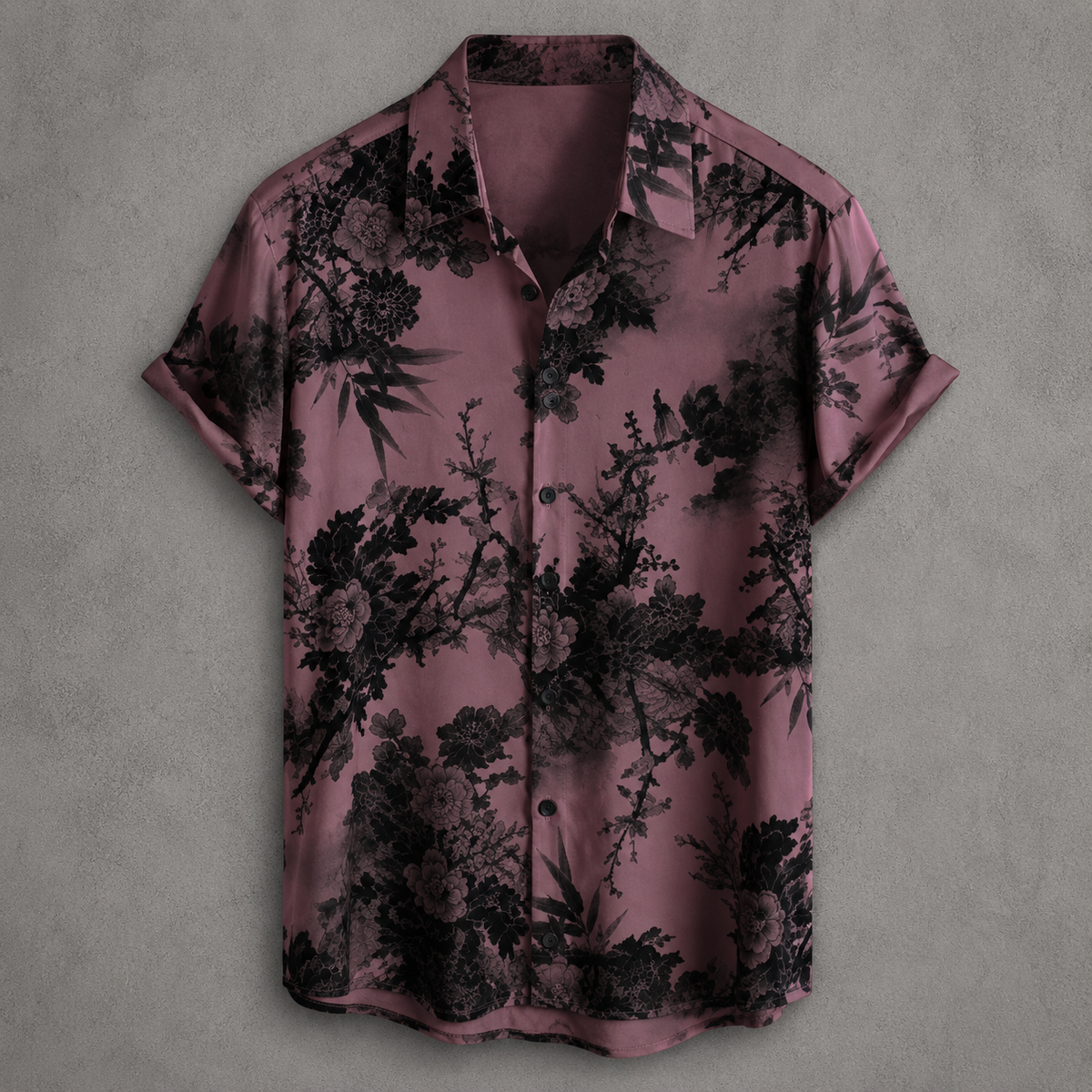 A short-sleeve button-up shirt in dusty mauve with a black floral and botanical print, displayed flat against a textured gray background.