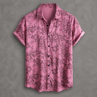 A short-sleeve button-up shirt in pink with a dark floral and botanical pattern, laid flat against a textured gray background.